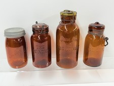 LOT OF 4: ATQ AMBER COLORED EMB MASONS JARS (GLOBE/LEADER/LIGHTNING/LONGLIFE)
