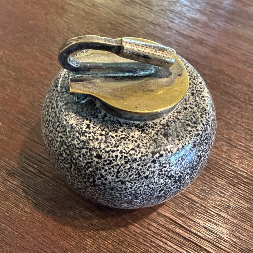 A miniature vintage curling stone repurposed as an inkwell — a wildly specific and utterly charming desk collectible.