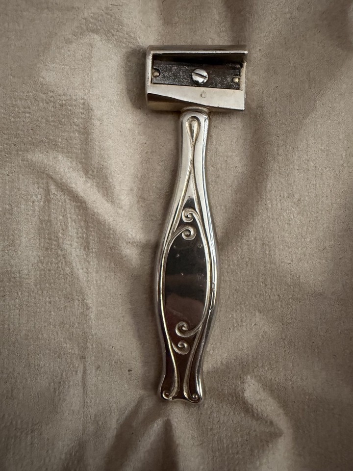 A silver-plated wand-style antique pencil sharpener — absurdly elegant and completely unlike anything you'd find in a modern office supply store.