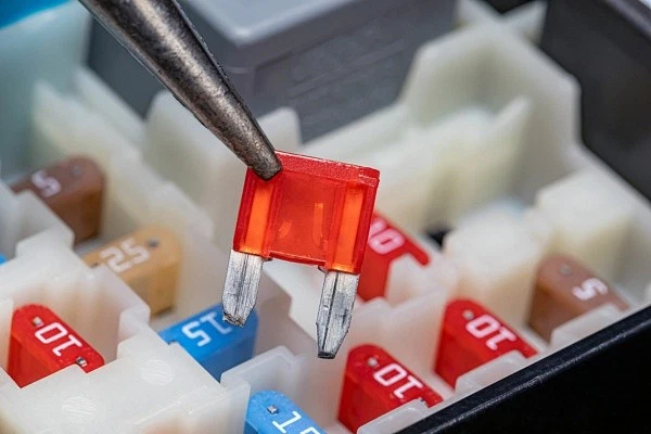 Pliers holding a broken or blown blade fuse