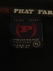 White fabric tag on black shirt with red “PHAT FARM” text, red and black logo, and “Made in U.S.A.” label.