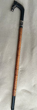 This is a hand-carved wooden walking stick featuring a distinct black horse-head