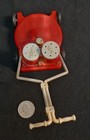 Red vintage plastic lawn mower with white wheels, salt & pepper shakers, and tan push handle on black background.
