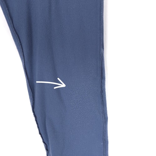 Close-up of a seam on a blue dress pant leg with white zigzag stitching and a small white arrow graphic.
