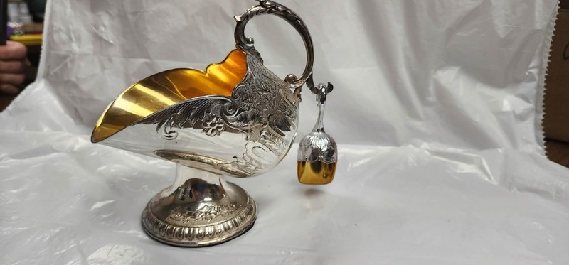 This vintage item is a silver-plated sugar scuttle with a "gold wash" or gilded