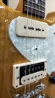 Cream and silver rabbit-shaped electric guitar with textured surface, black pickguard, and six strings.