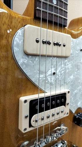 Cream and silver rabbit-shaped electric guitar with textured surface, black pickguard, and six strings.