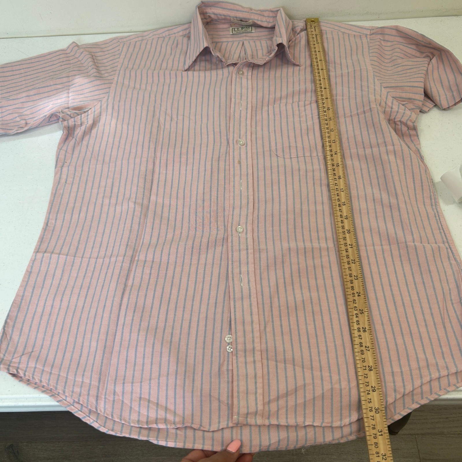 Light pink short sleeve Oxford shirt with vertical blue and pink stripes, button-down collar, and white cuff and placket buttons.
