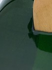 Green SCHECTER PA-SW/TH/See-Thru electric guitar with silver hardware, shown with a wooden polishing cloth on the surface.
