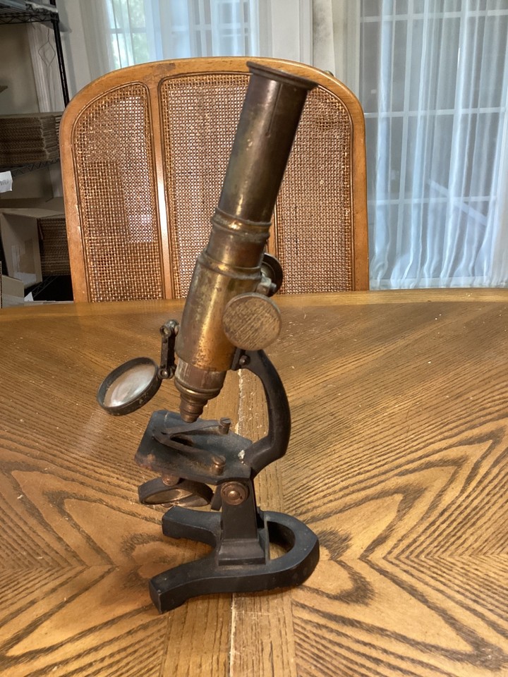 A brass and cast-iron monocular compound microscope from the late 19th/early 20th century — a stunning steampunk-era scientific artifact that doubles as jaw-dropping desk sculpture.