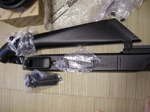 Black Toyota 70 Series Land Cruiser air intake snorkel set in clear plastic packaging on a beige carpet.