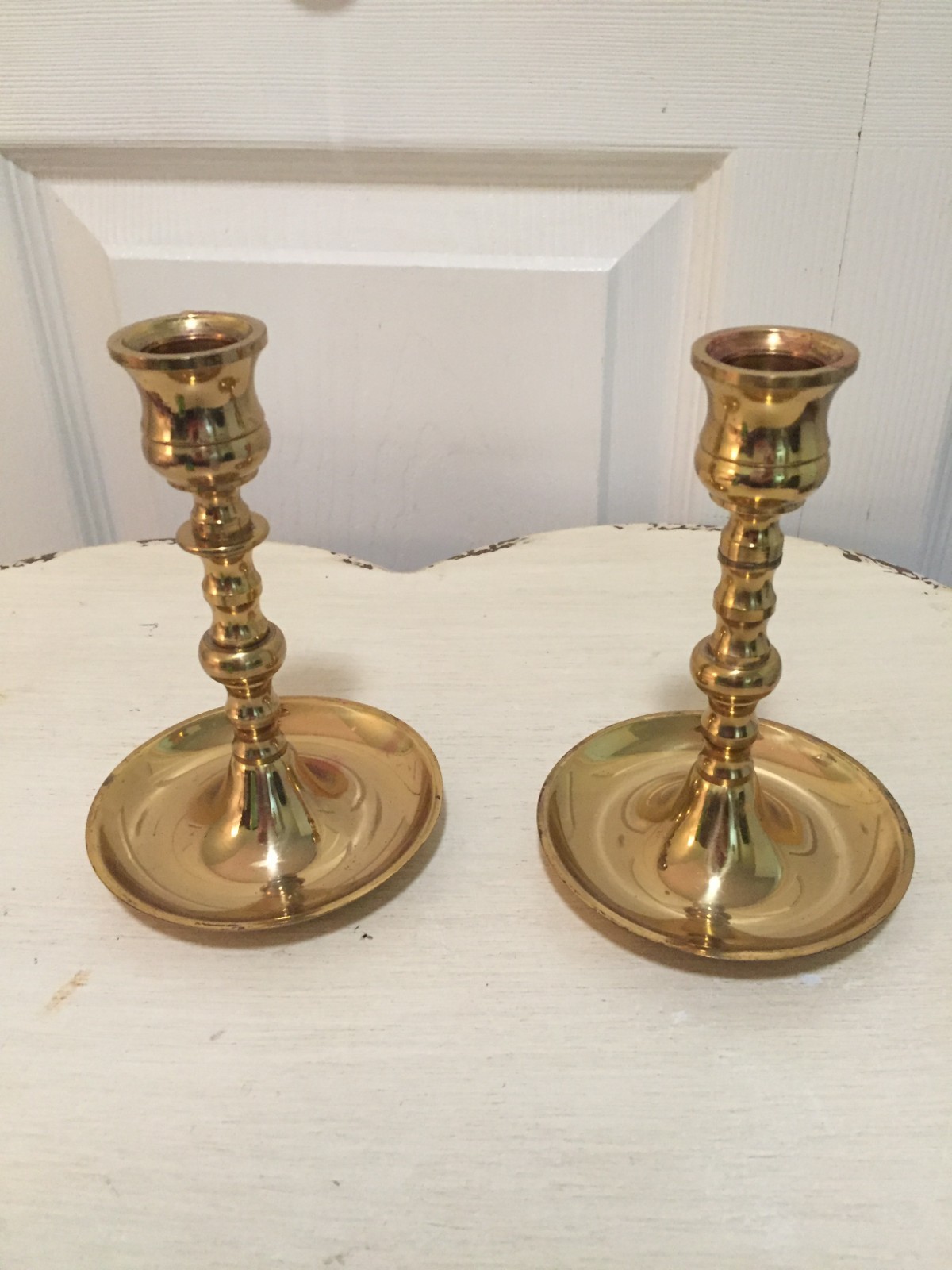 Pair of brass candlestick holders with round bases and traditional taper design.