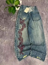Y2K baggy denim jeans with bold tribal embroidery down the leg. Wide-leg fit wit