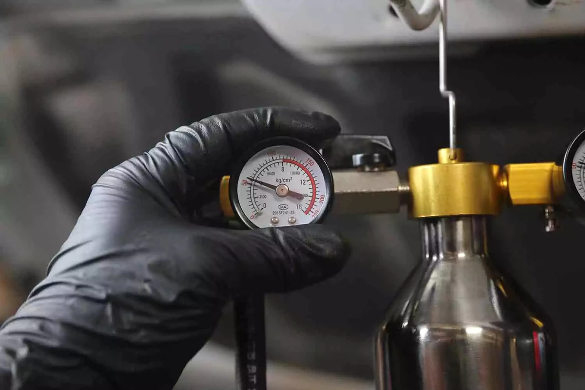 A mechanic wearing a black glove opens the feed-line valve.