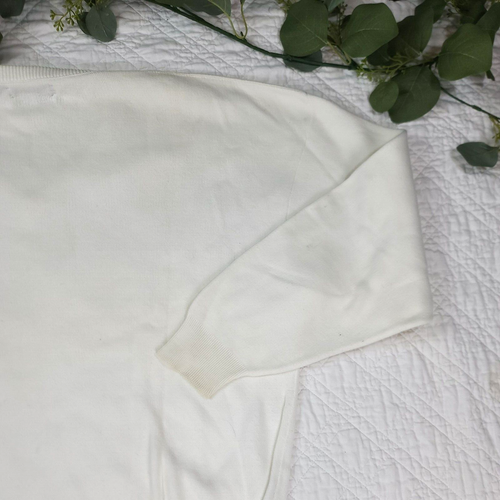 White VTG Christian Dior men’s V-neck sweater with long sleeves and ribbed cuffs, made in USA, on a quilted fabric surface.