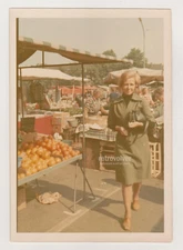 Elegantly Dressed Woman Navigates the Fruit and Veggie Stalls in Market Snapshot
