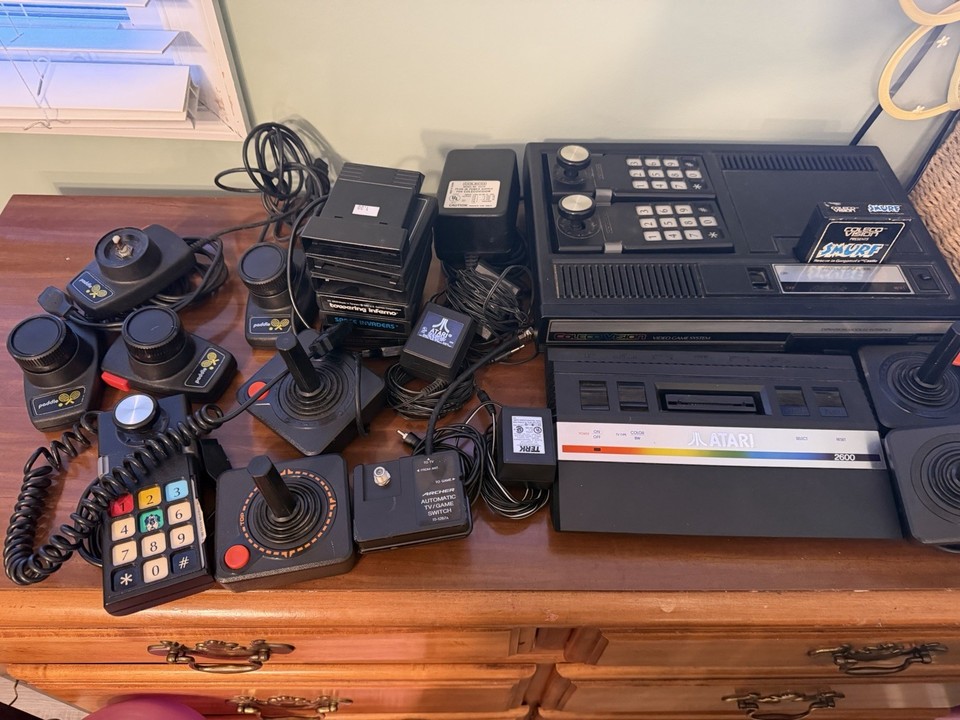 A rare Atari 2600 Jr. Rainbow edition bundled with a Coleco system and 8 games — a dual-console vintage lot that's as much wall-art as it is gaming history.