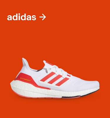 A side shot of a white adidas running shoe with bright orange stripes and features.