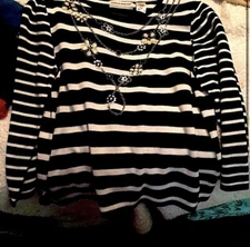 Black and white stripped shirt with chain connecting flower designed necklace.