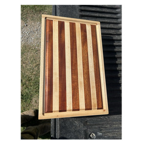 Handmade cutting board made out of various strips of Mahogany and Maple.