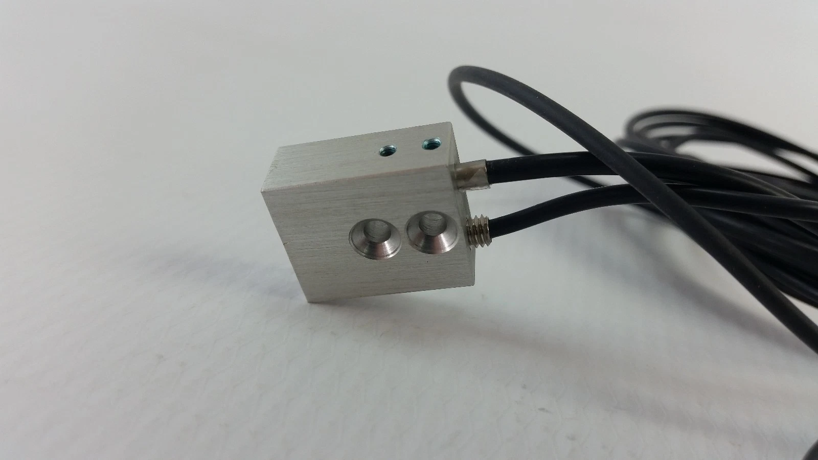 Aluminium mounting block holding two fiber-optic heads connected to the E3X-DA11-N