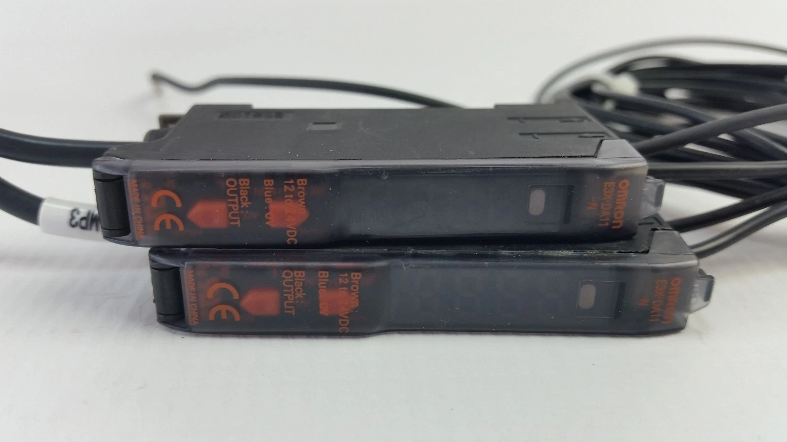 Two E3X-DA11-N amplifiers side by side with orange wiring labels and CE marks