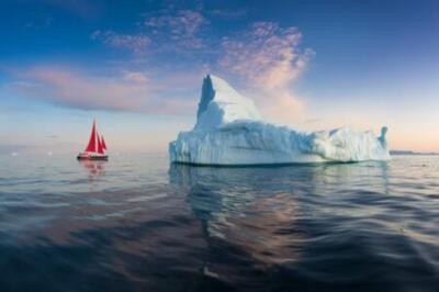 Wandbild: Ein kleines Boot zwischen Eisbergen. Segelbootfahrt zwischen [...]