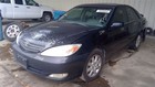 Black Toyota Camry 2002-2006 with front bucket passenger retractor, silver wheels, and visible white Toyota logo on hood.