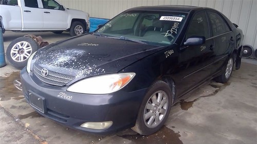 Black Toyota Camry 2002-2006 with front bucket passenger retractor, silver wheels, and visible white Toyota logo on hood.