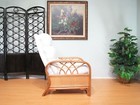 White rattan recliner chair with padded backrest and armrests, placed on light green wall with black circular fence.
