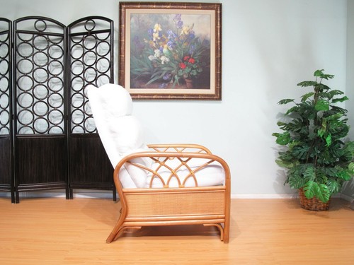 White rattan recliner chair with padded backrest and armrests, placed on light green wall with black circular fence.