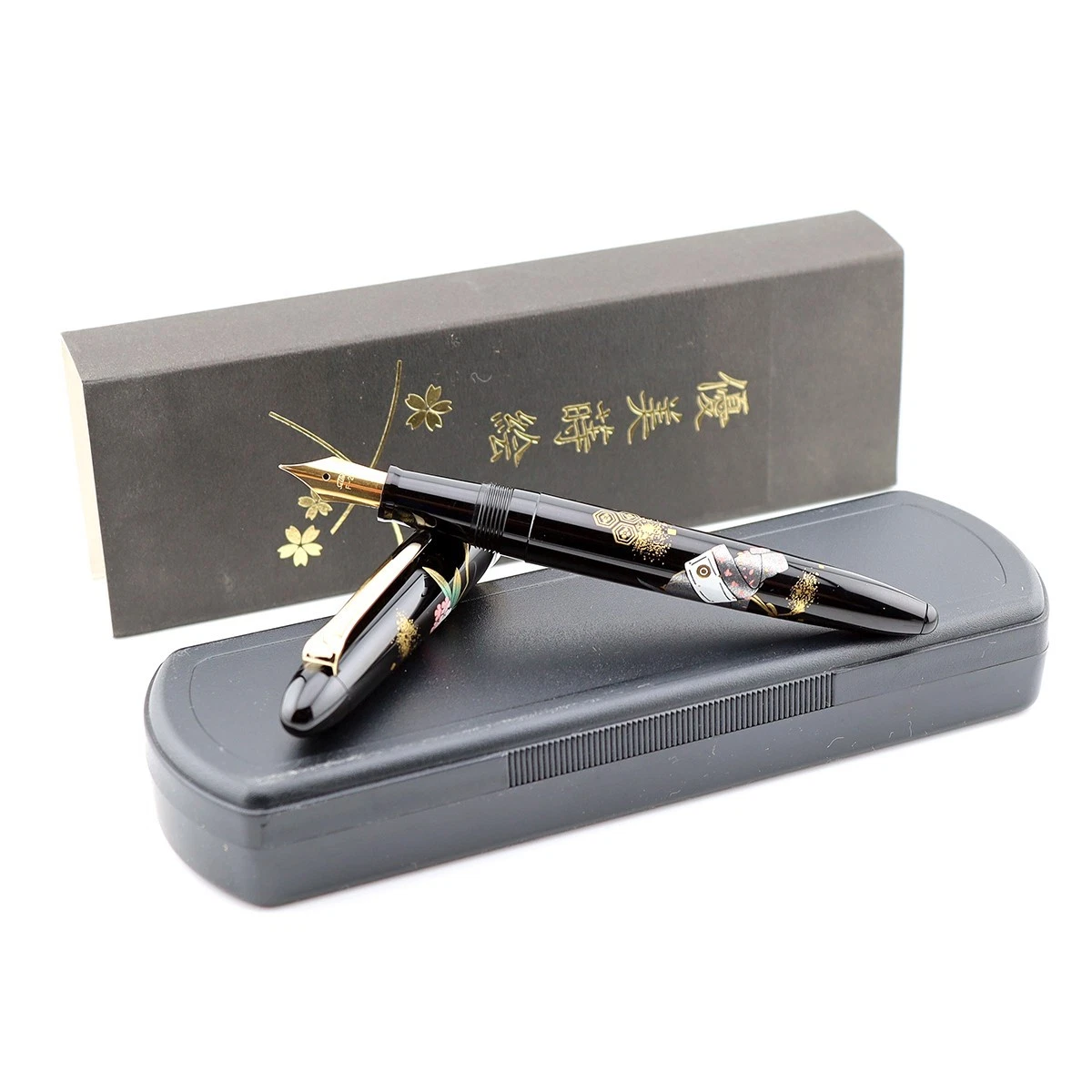 Black Sailor Maki-e fountain pen with gold and green dragon design in open box, next to labeled green pen holder.