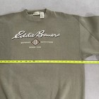 Olive green vintage Eddie Bauer sweatshirt size L with white “Outdoor Hip Hop USA Made 90s” text and red eagle logo on chest.