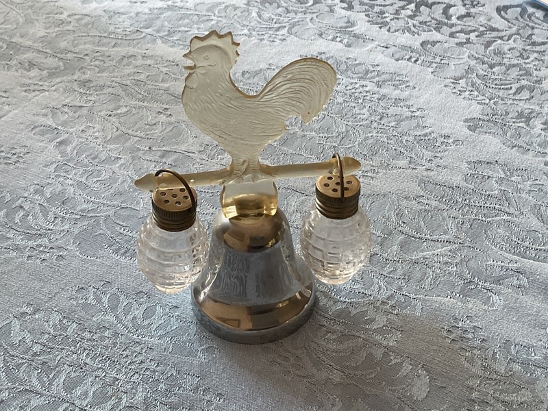 Vintage salt and pepper shakers hanging from a lucite rooster and bell