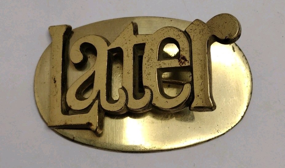 A brass paperweight literally engraved 'LATER' — procrastination elevated to an art form and a genuine conversation piece.