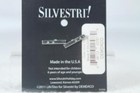 Black card with silver metal pendant shaped like a bent nail, white label reading “Demdaco” and barcode.