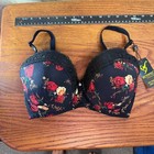 Black padded underwire bra with red rose floral print, black lace trim, and yellow “Binnys” tag on front.