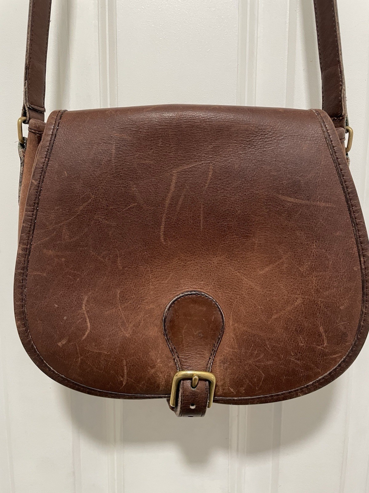 Dark brown leather saddle bag with buckle flap closure, Coach.