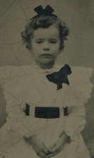 YOUNG CURLY HAIRED GIRL WEARING BOWS. TINTYPE.