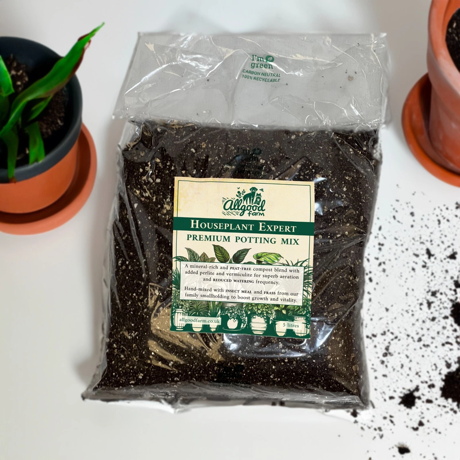 Bag of houseplant potting soil on white table with plant pots