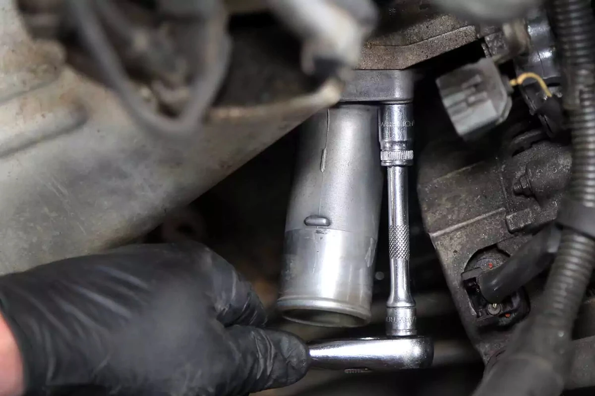 Tightening a nut on the thermostat housing with a socket wrench.