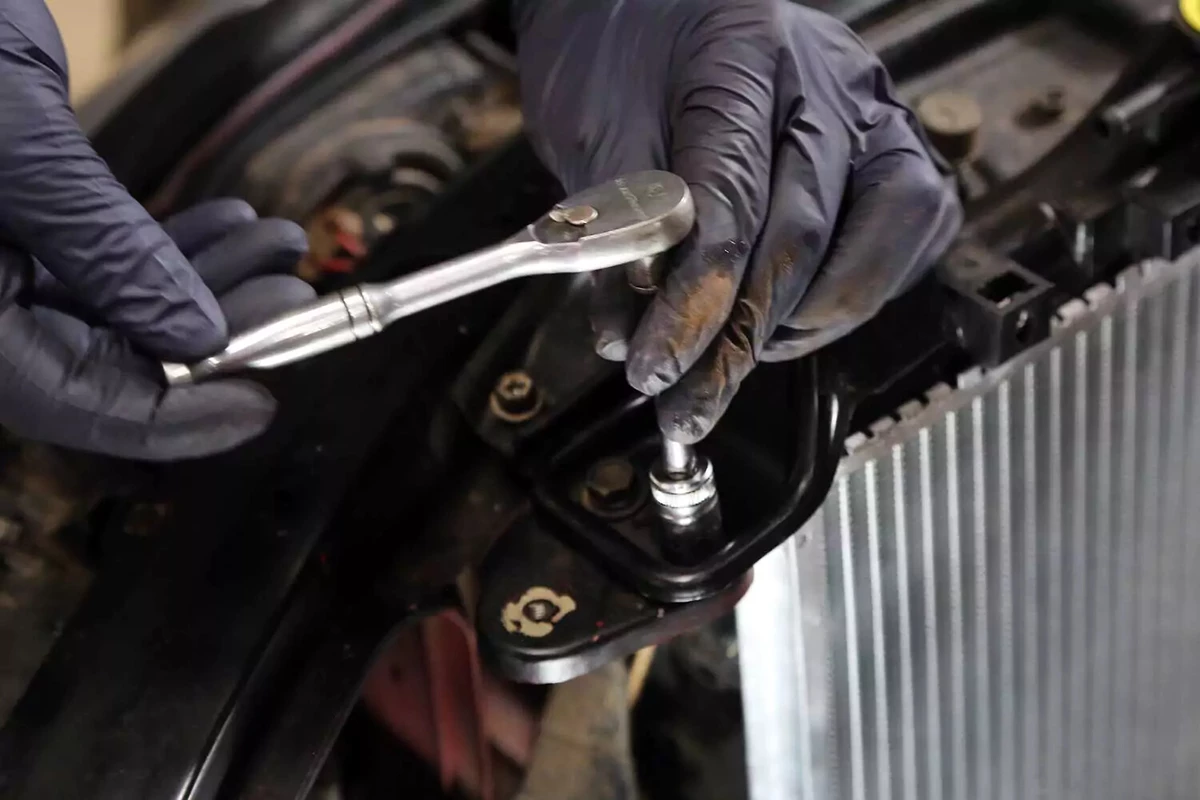 Reinstalling the upper radiator mount with a socket wrench.
