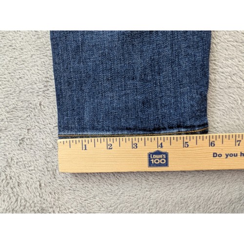 Folded dark blue Rag & Bone Fit 2 slim jeans with gold trim, shown beside a wooden ruler measuring approximately 12 inches.