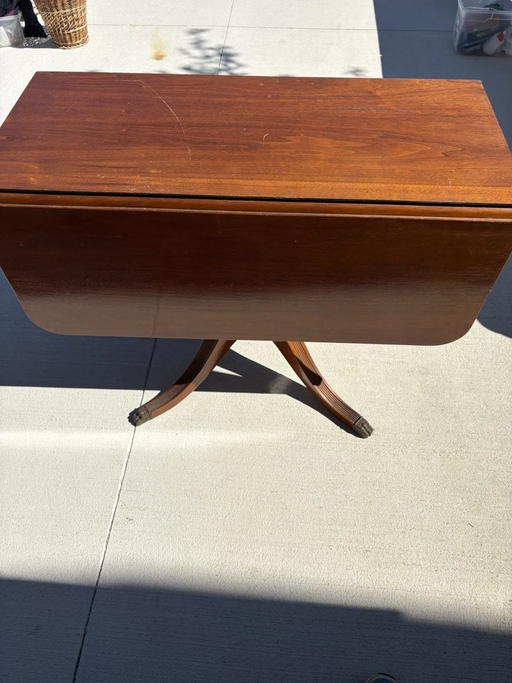 Antigua mesa con patas de madera con hojas caídas con un cajón. Foto 3 de 4