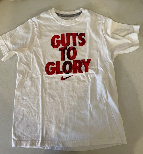 Camiseta blanca NIKE, juvenil, talla mediana, con gráfico rojo ""GUTS TO GLORY"". Usado. - Imagen 5 de 9