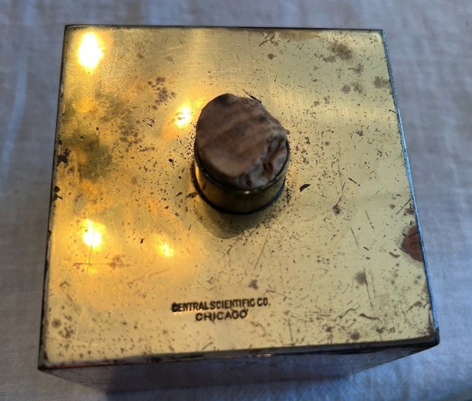 A mysterious vintage science cube housing four distinct metals (brass, copper, steel, nickel) from a real scientific supply company — basically a tactile puzzle artifact from a lab that no longer exists.