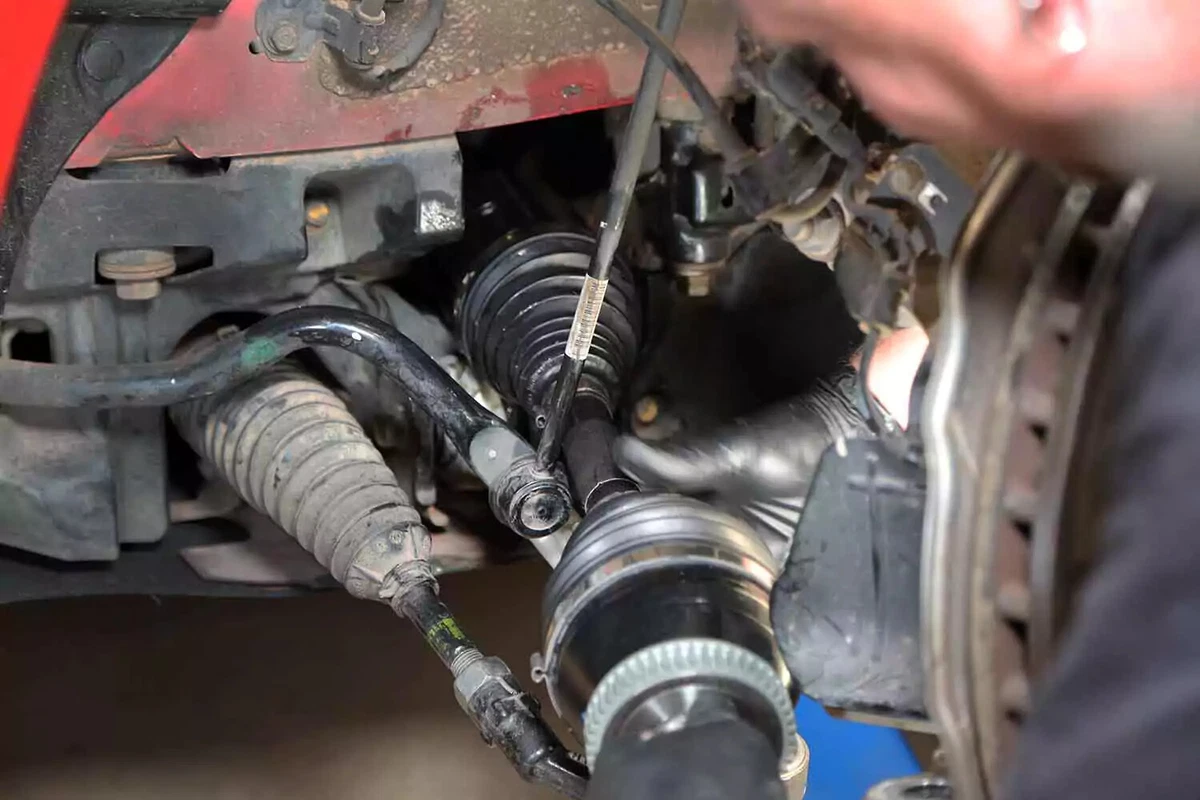 A mechanic slides the new CV axle shaft into the cavity.