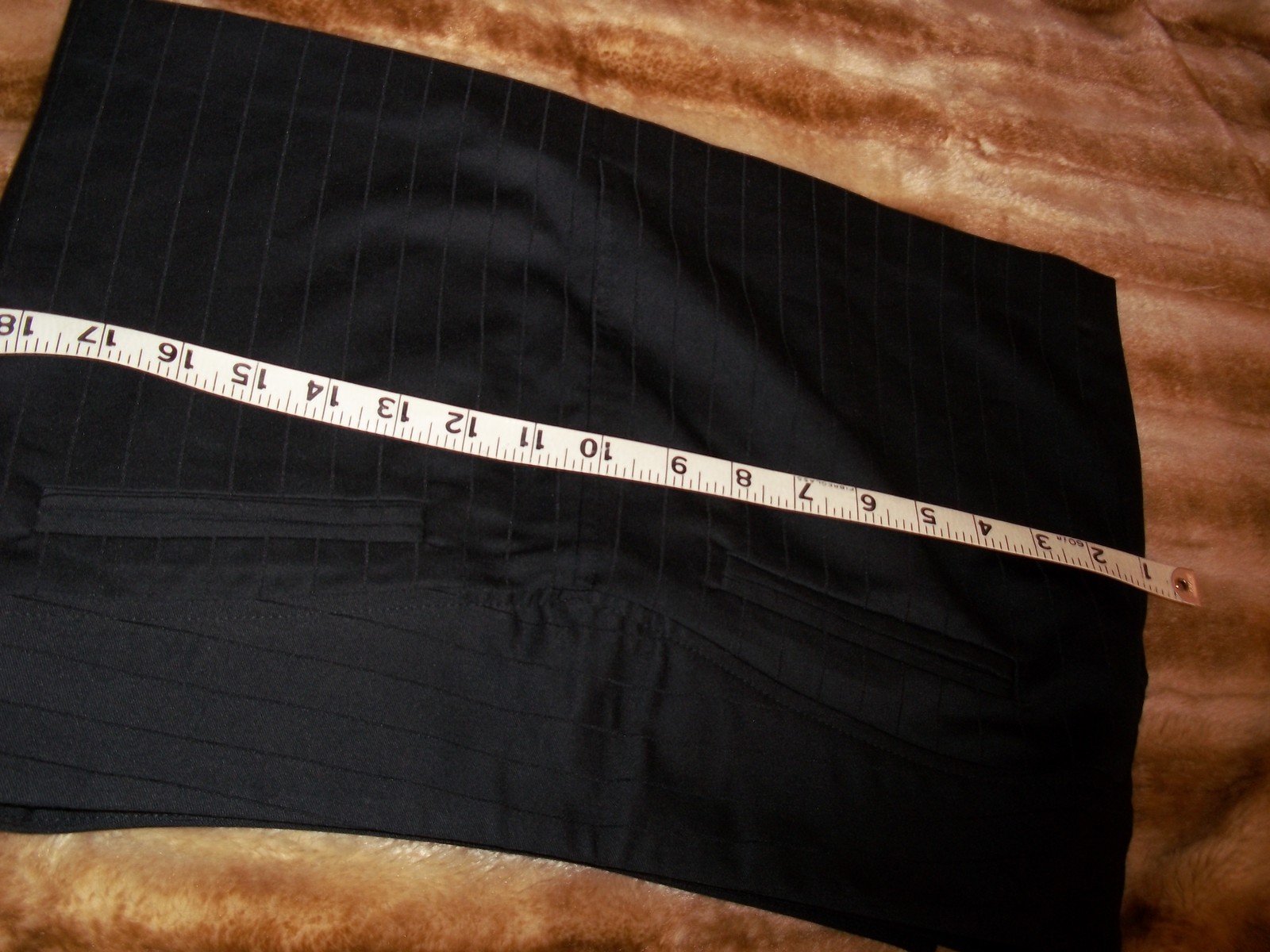 Black mini skirt with vertical pin stripes, white measuring tape, and “MADE IN USA” label at bottom.