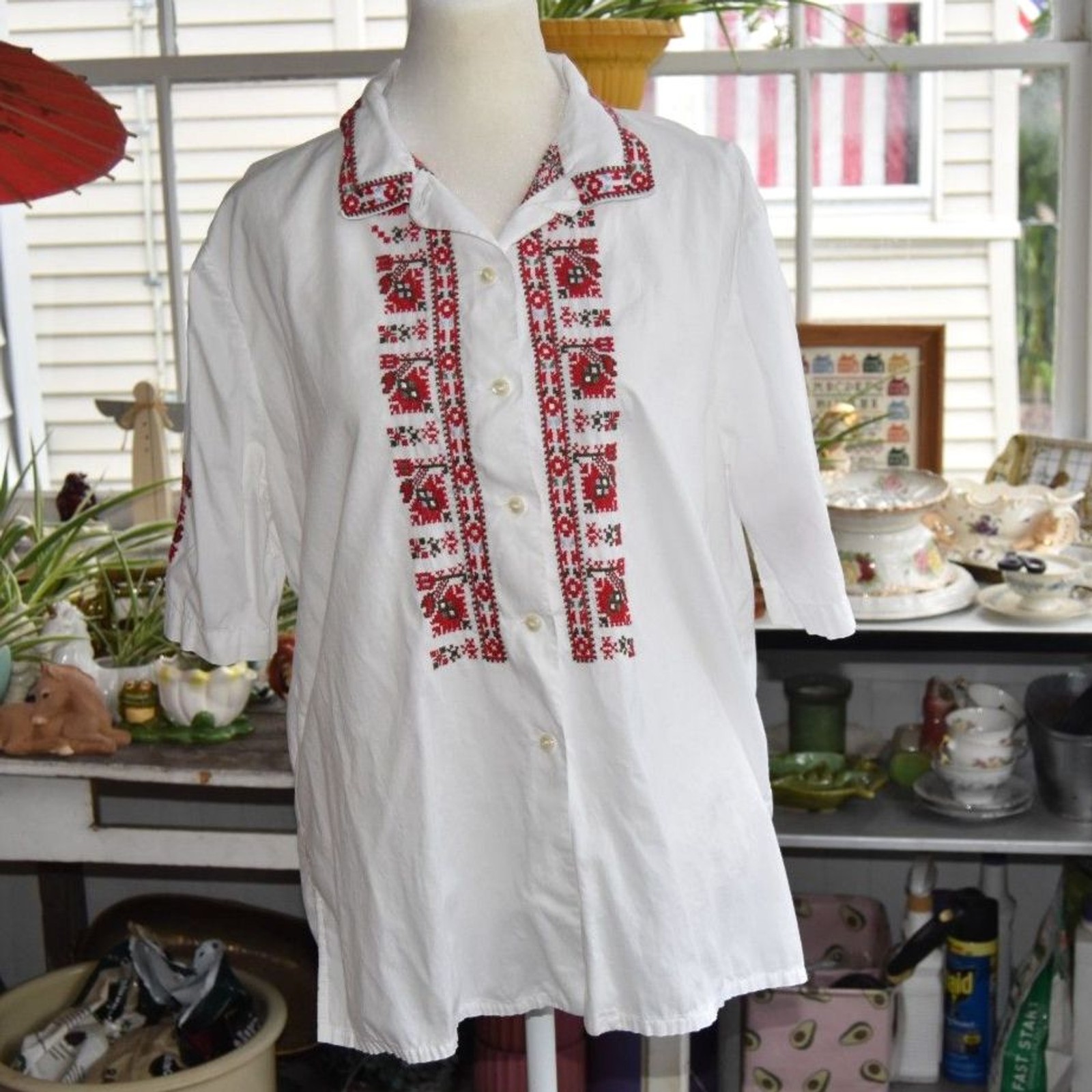 White cotton peasant blouse with hand embroidery along the neckline, laid flat