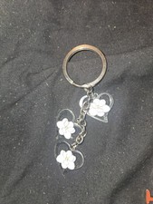 silver-toned metal keychain featuring three heart-shaped charms with white...